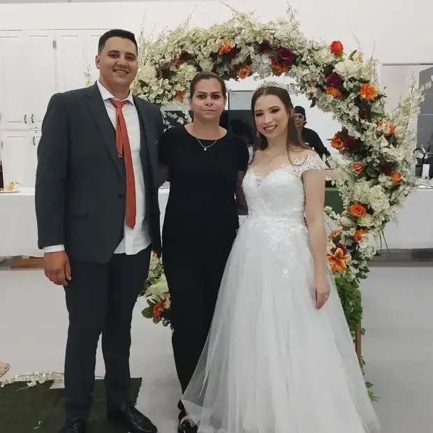 Noivos com a equipe no arco de flores
